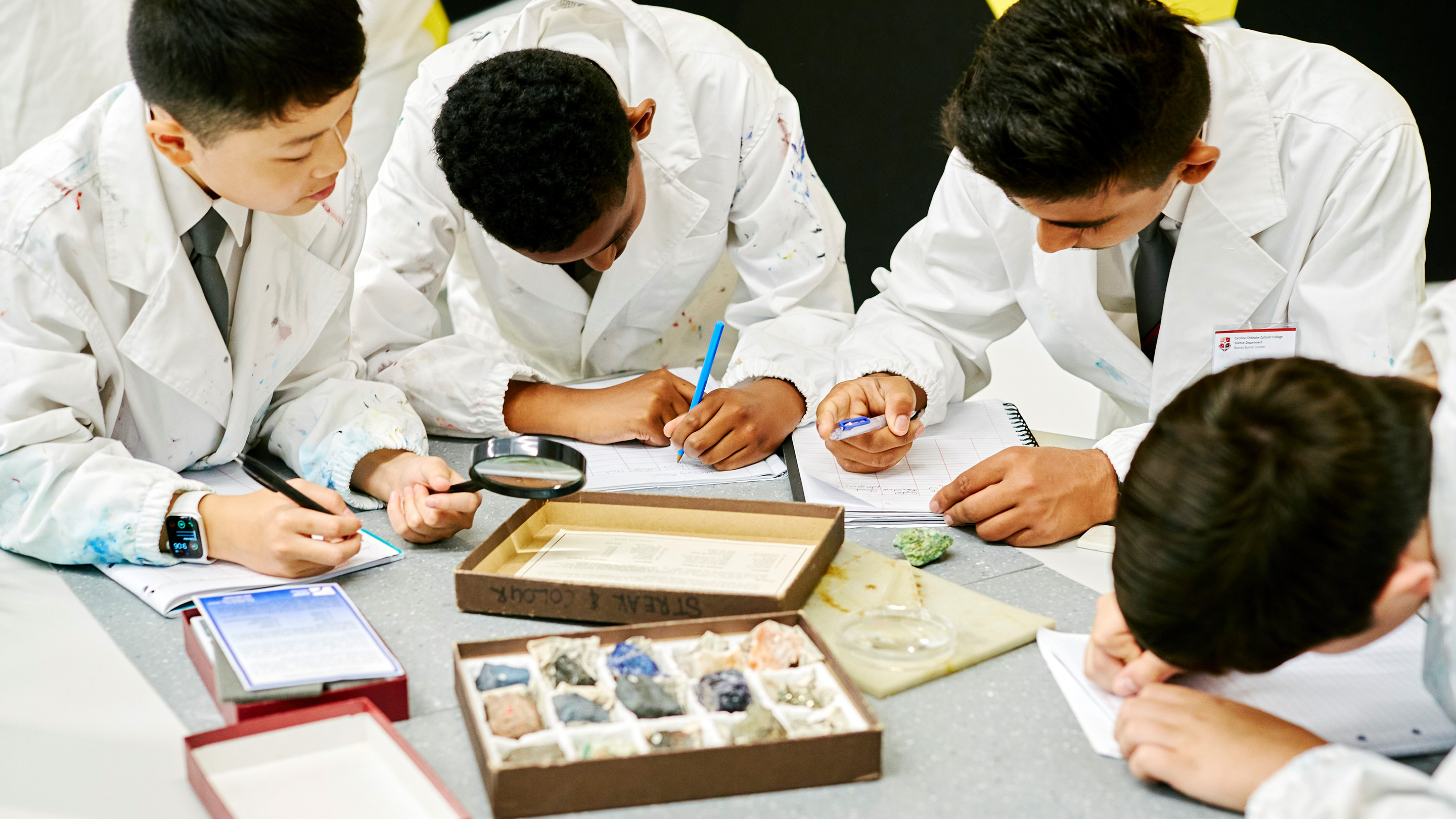Four secondary students standing around a bench, doing a science experiment.