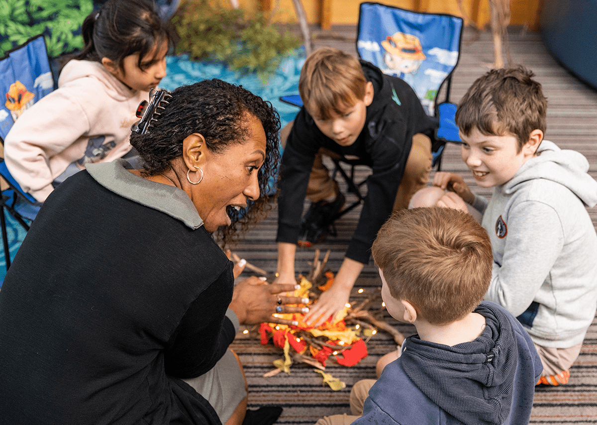 Photo of educator playing with children in a circle.