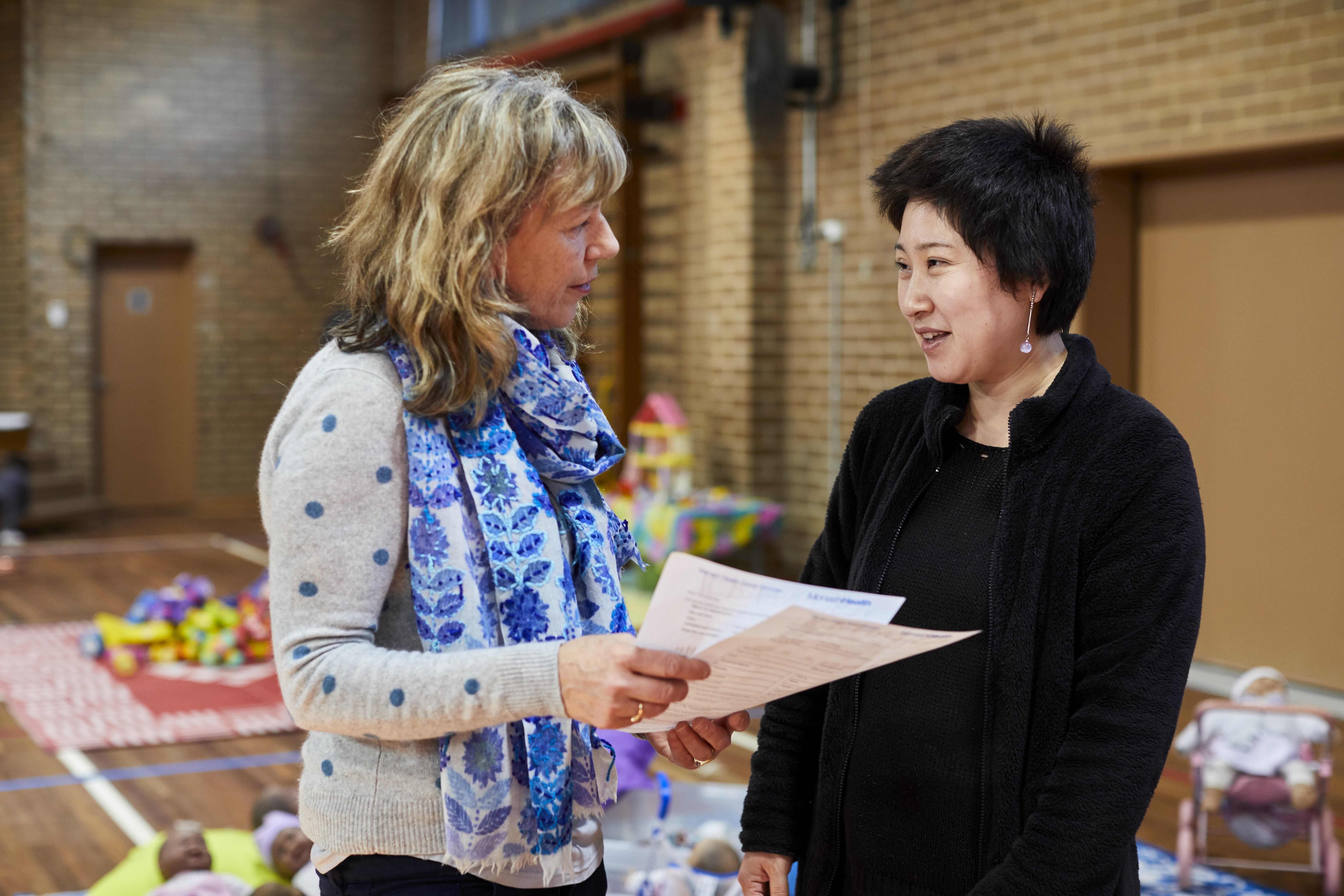Two adults in a school hall, engaged in conversation 