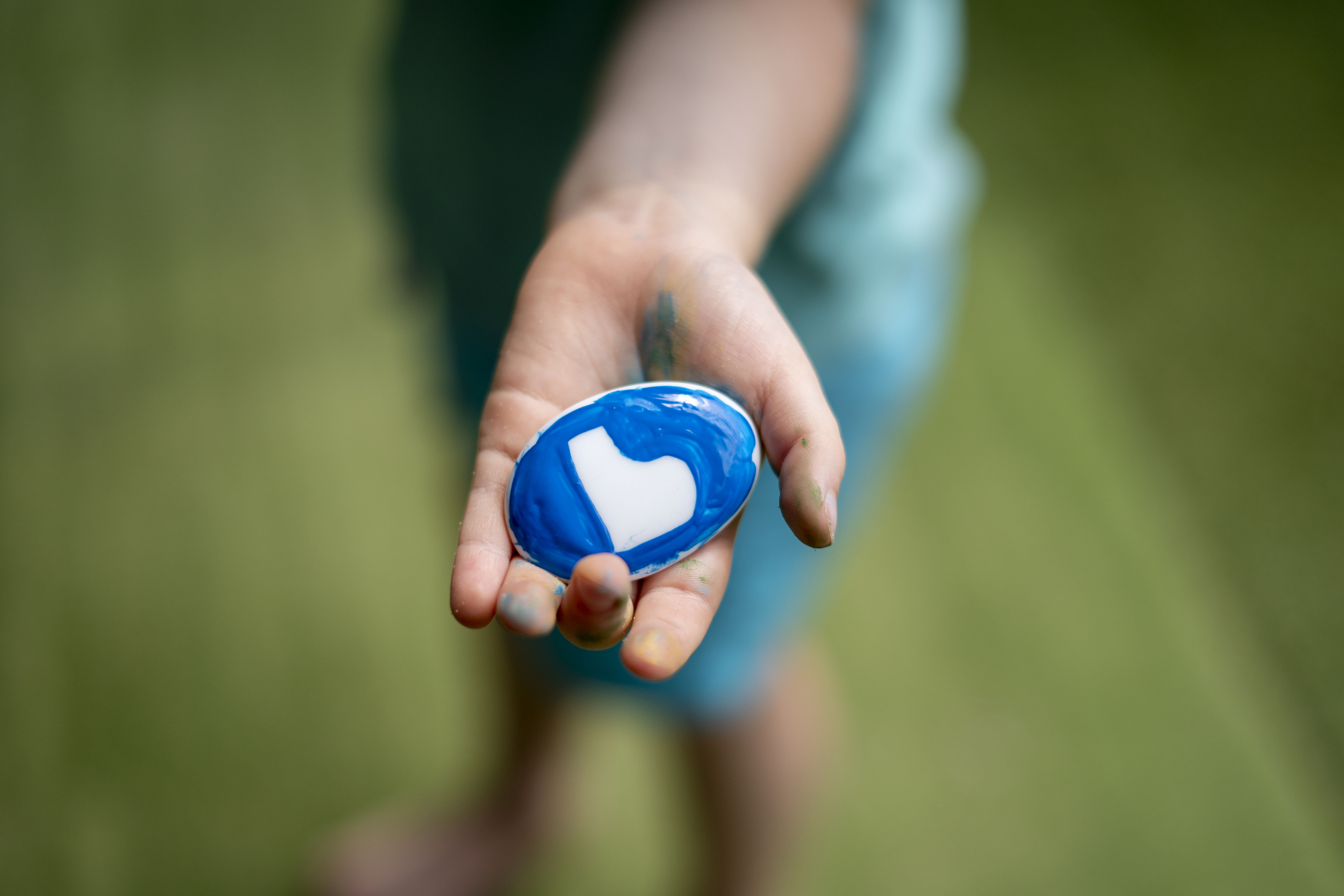 A child holding a stone painted with the Be You logo 
