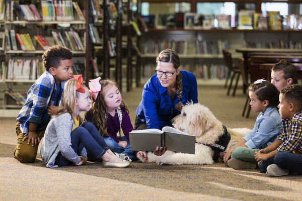 An educator reading to a group of young children in a library